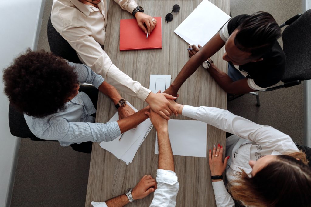 Les collaborateurs d'une entreprise pose leurs mains les unes sur les autres sur une table de travail, pour symboliser l'esprit d'équipe